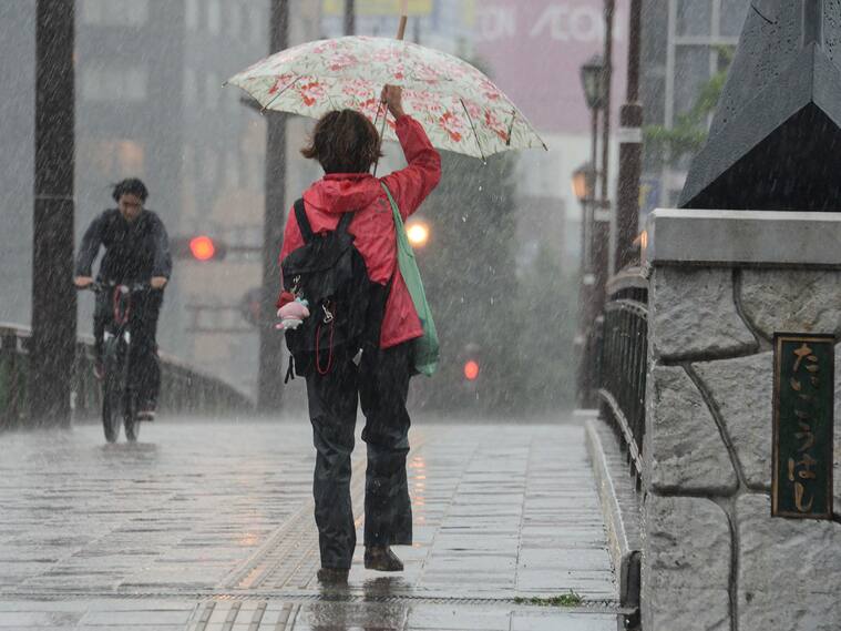 Mujer se cubre de las fuertes lluvias en la isla de Kyushu en Japón