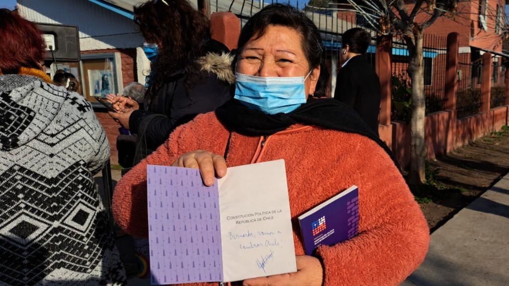 Una vecina que llegó hasta el lanzamiento de la campaña muestra la firma del Presidente Boric en la propuesta de nueva Constitución. / ADN.cl