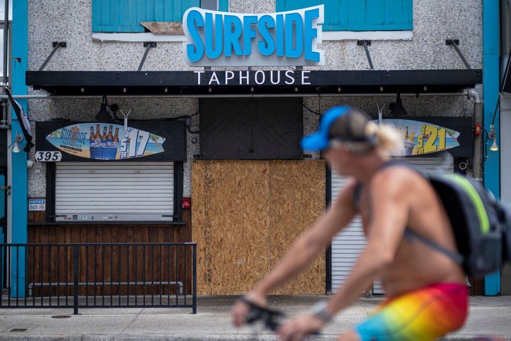 Ciclistas observa las tiendas protegidas por arribo de huracán a Florida
