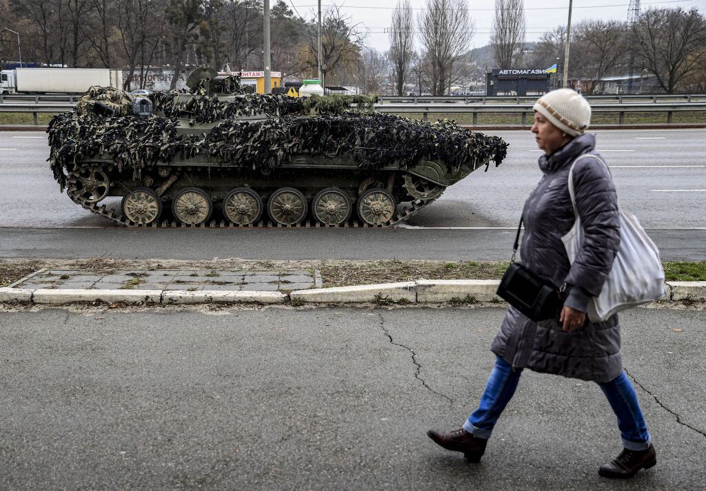 Una mujer camina frente a un tanque por una calle de Kiev