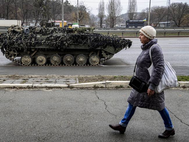 Una mujer camina frente a un tanque por una calle de Kiev
