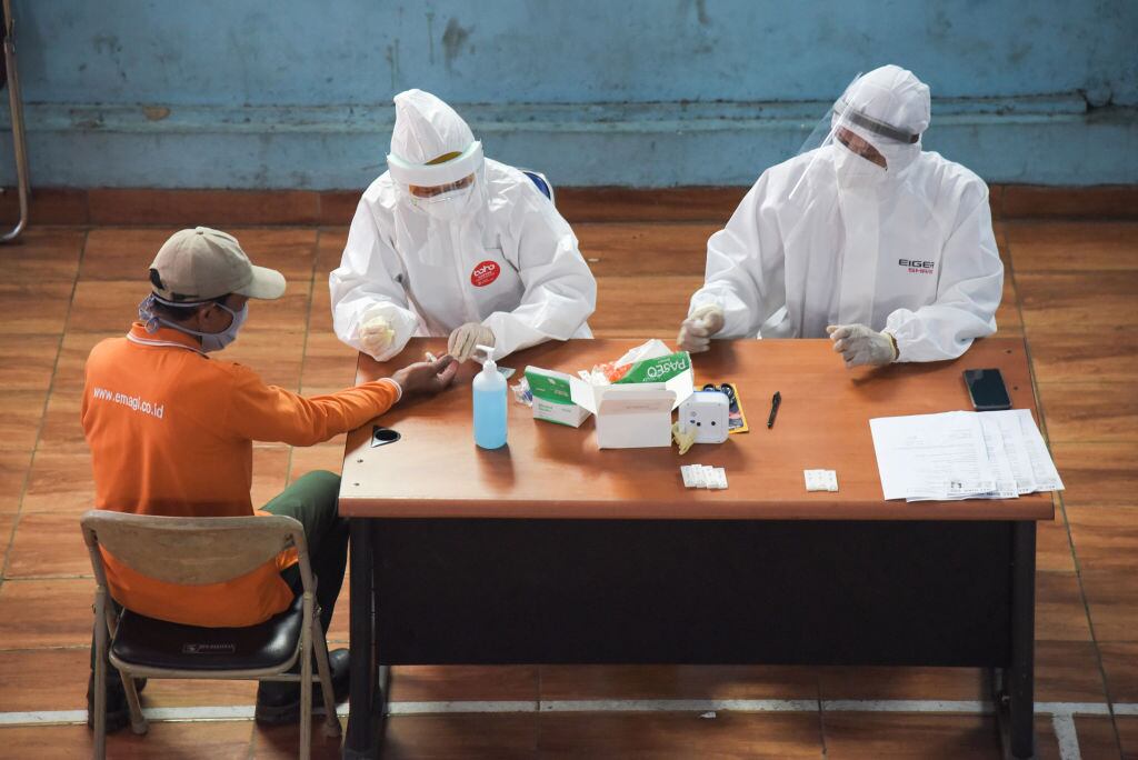 Medical personnel take a blood sample from a man during the Covid-19 rapid test at Banjaran Market, Bandung Regency, West Java, Indonesia, June 11, 2020. (Photo by: Asep Solihin/INA Photo Agency/Universal Images Group via Getty Images)