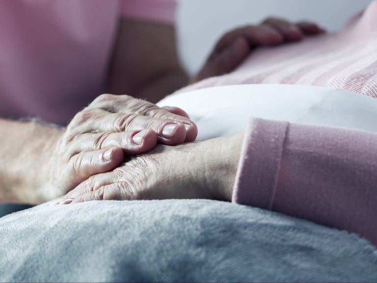 Senior man holding hand of his ill wife, close up