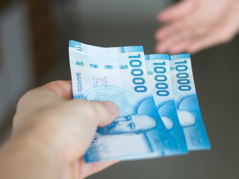 High resolution image. Hands giving and receiving chilean money notes. Chile ten thousand (10000) pesos. Selective focus.