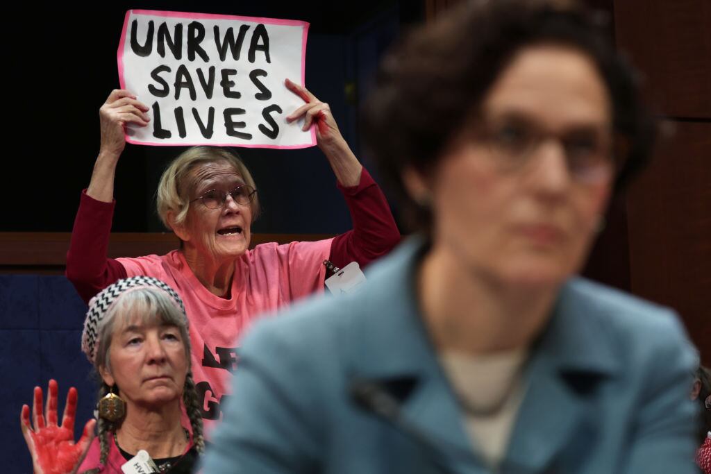 Manifestantes muestran carteles en apoyo a la labor de la UNRWA en Gaza, en una sesión de una comisión de cancillería en el Congreso de Estados Unidos.