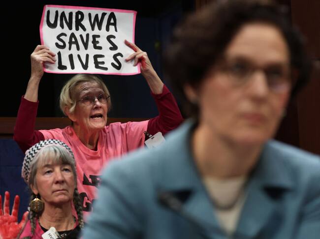 Manifestantes muestran carteles en apoyo a la labor de la UNRWA en Gaza, en una sesión de una comisión de cancillería en el Congreso de Estados Unidos.