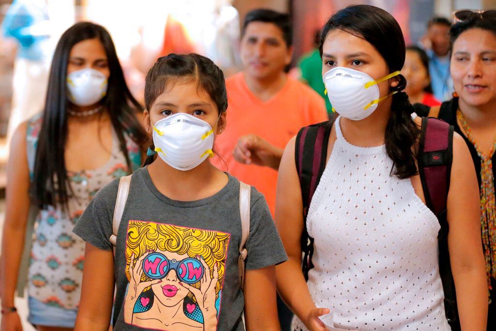 Unas personas con mascarillas salen desde el Aeropuerto de Lima