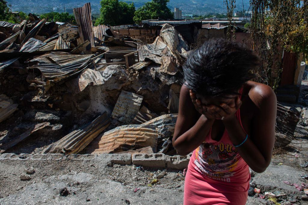 Una mujer llora frente a una casa incendiada por un grupo criminal en la ciudad de Puerto Príncipe en Haití