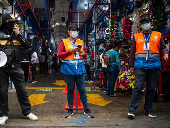 Personal de seguridad vigila el uso del carnet de vacunación en un local en Lima