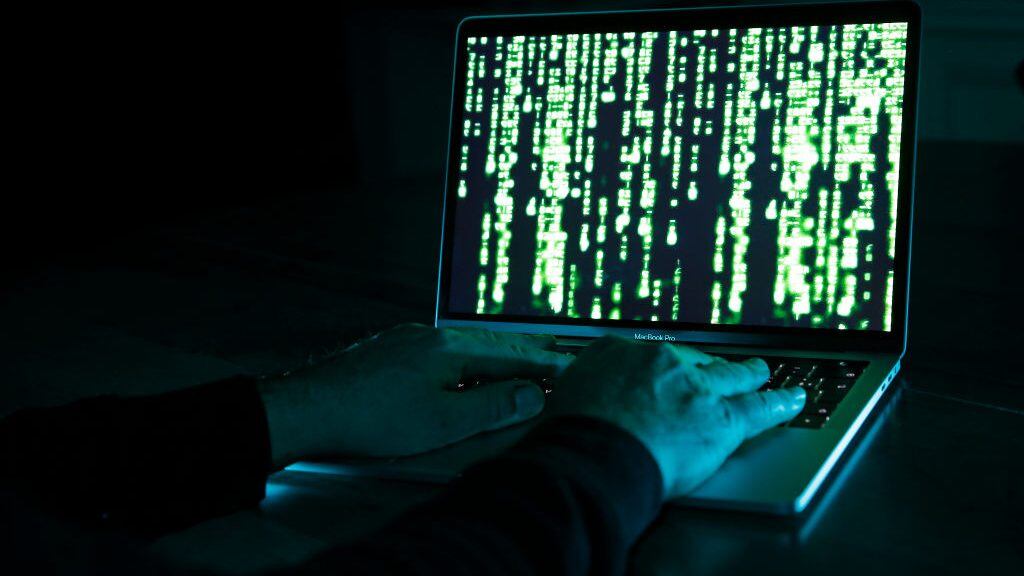 PARIS, FRANCE - DECEMBER 27: In this photo illustration, a hacker with an Anonymous mask on his face and a hood on his head uses a computer on December 27, 2019 in Paris, France. In IT security, a hacker is an IT specialist, who is looking for ways to bypass software and hardware protections. Hackers are generally intelligent programmers who seek to manipulate or modify a computer system or network. (Photo by Chesnot/Getty Images)