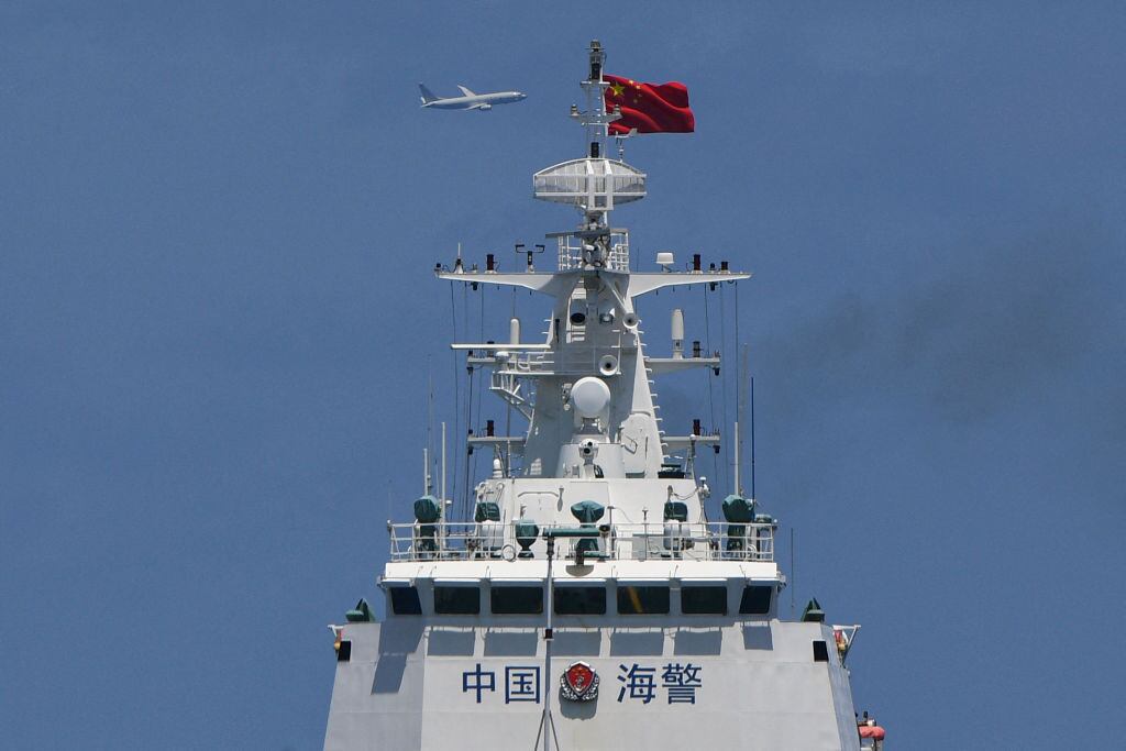 Una nave de la guardia costera de China navega cerca de sus costas mientras pasa por los aires el avión militar P-8 Poseidon de Estados Unidos