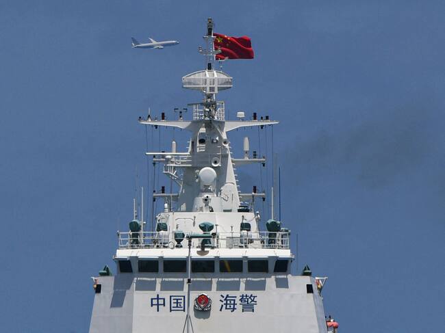 Una nave de la guardia costera de China navega cerca de sus costas mientras pasa por los aires el avión militar P-8 Poseidon de Estados Unidos