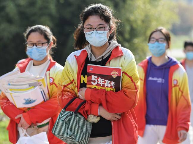 Tres estudiantes llegan a su escuela utilizando máscaras en la ciudad china de Bozhou