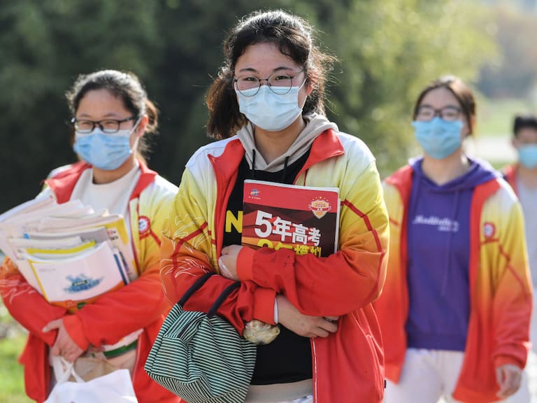 Tres estudiantes llegan a su escuela utilizando máscaras en la ciudad china de Bozhou