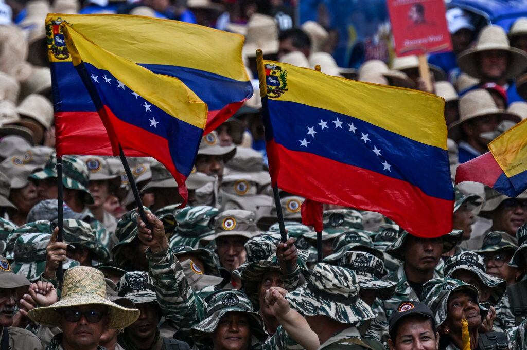 Miembros de las fuerzas armadas de Venezuela marchan con banderas de su país durante un evento conmemorativo en la ciudad de Caracas