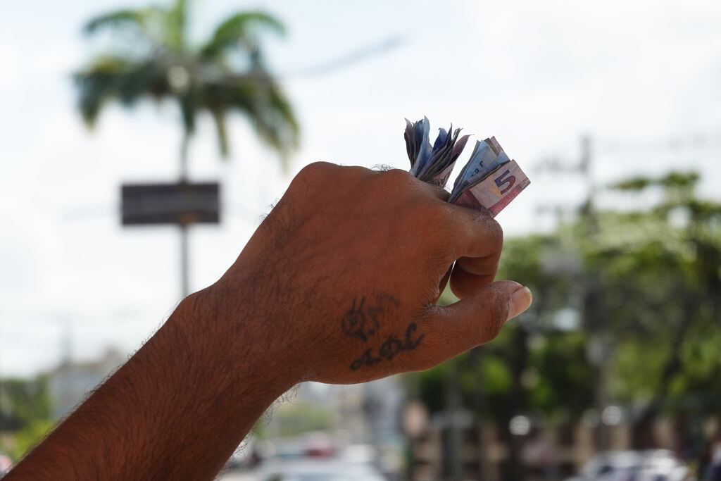 Un hombre en la ciudad de Recife, del estado de Pernambuco, lleva dinero en medio de sus dedos por la calle en Brasil.