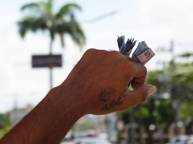 Un hombre en la ciudad de Recife, del estado de Pernambuco, lleva dinero en medio de sus dedos por la calle en Brasil.