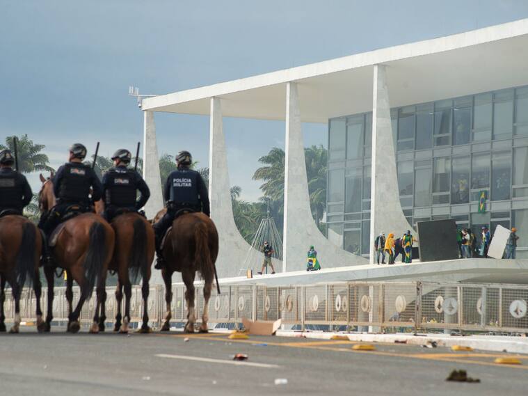 Policías ven cuando los ultraderechistas atacan el palacio de gobierno de Brasil