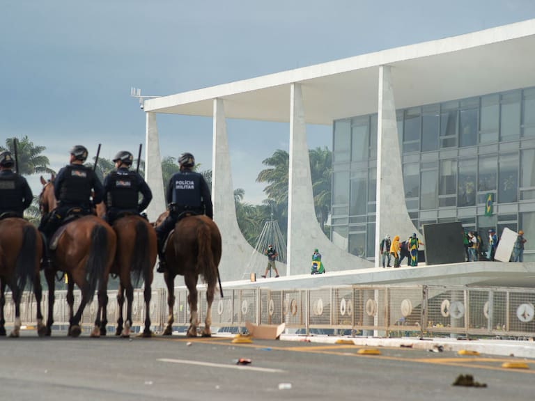 Policías ven cuando los ultraderechistas atacan el palacio de gobierno de Brasil
