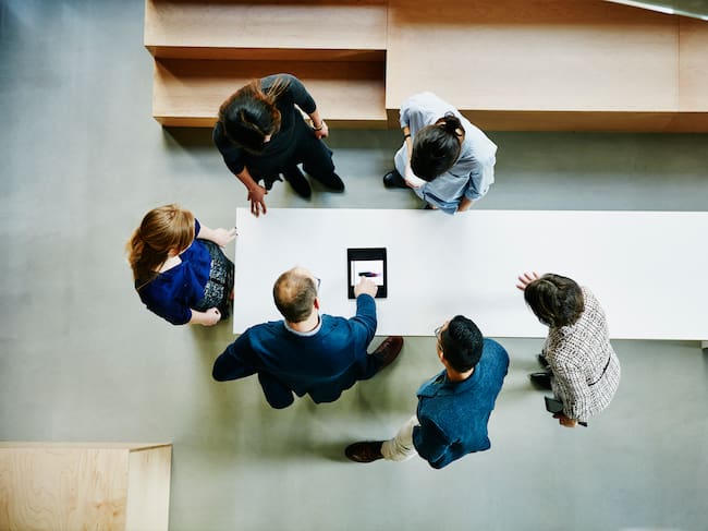 Overhead view of business colleagues discussing project on digital tablet