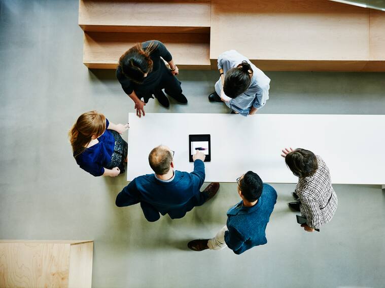 Overhead view of business colleagues discussing project on digital tablet