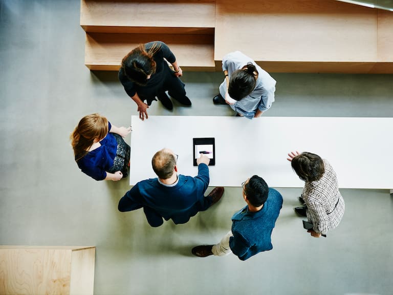 Overhead view of business colleagues discussing project on digital tablet