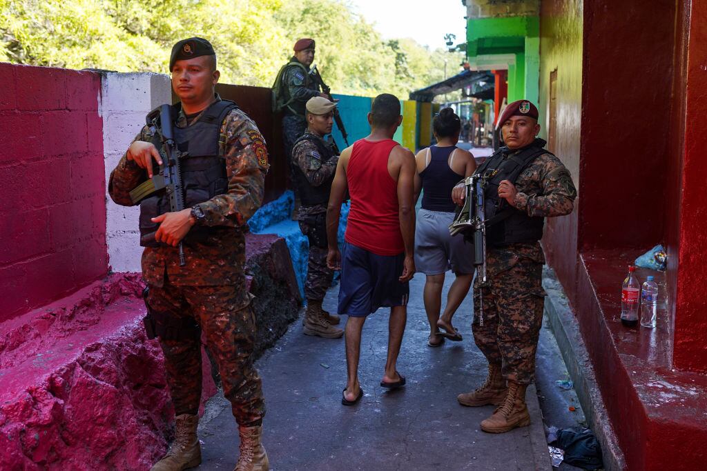 Las personas caminan entre militares armados en las calles de El Salvador