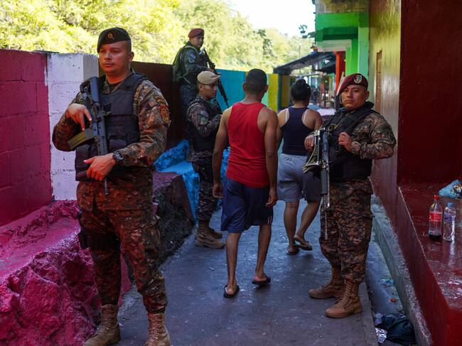 Las personas caminan entre militares armados en las calles de El Salvador