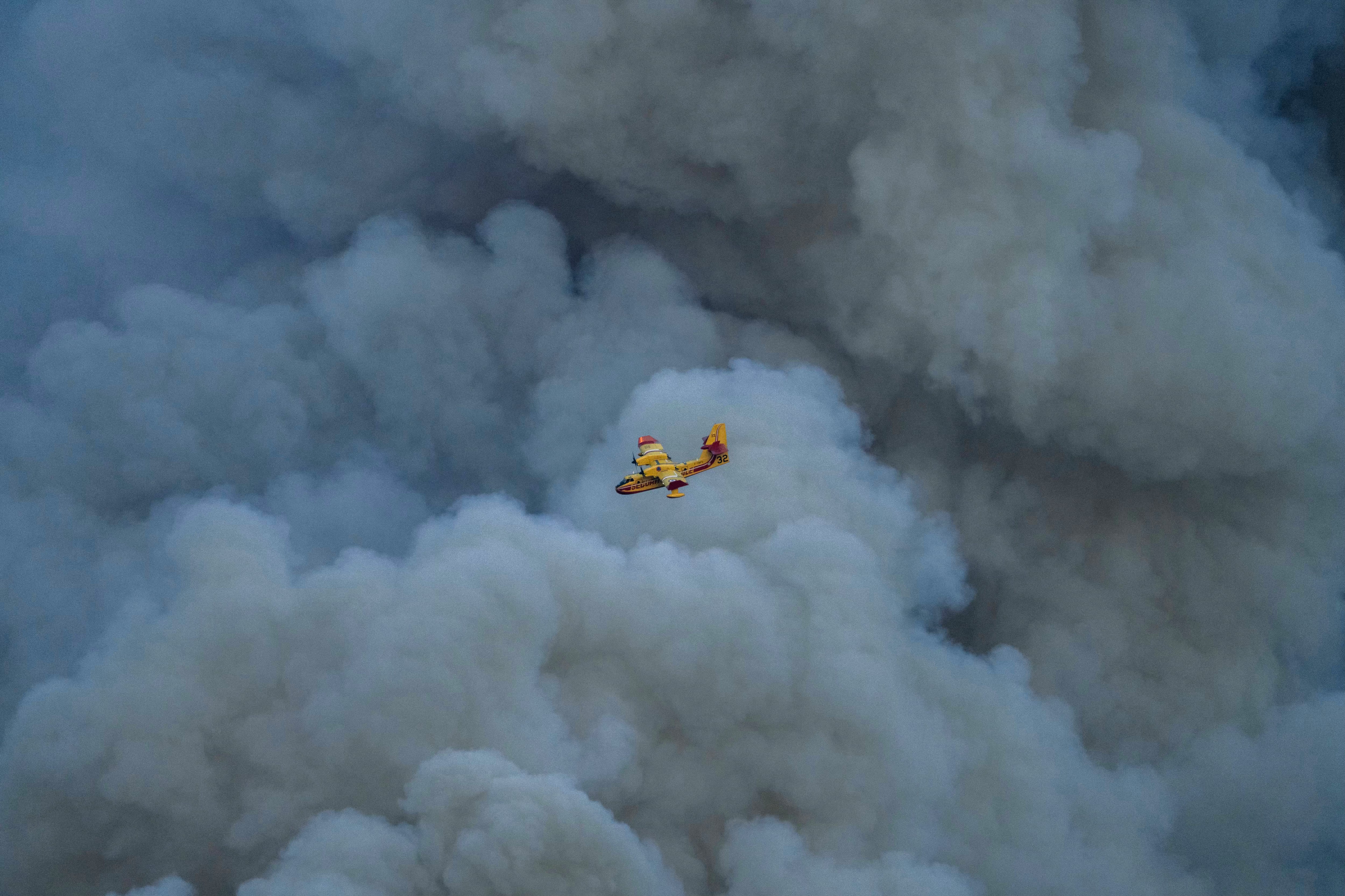 TOPSHOT - A Canadair CL-415 of the French civil security flies over a wildfire in Jonquières, southwestern France, on August 5, 2025. A fire that broke out on August 5, 2025 afternoon in Ribaute (Aude) has burned 4,000 hectares of forest and scrubland in just a few hours before reaching the village of Saint-Laurent-de-la-Cabrerisse, where houses were burned down. (Photo by Idriss BIGOU-GILLES / AFP) (Photo by IDRISS BIGOU-GILLES/AFP via Getty Images)          