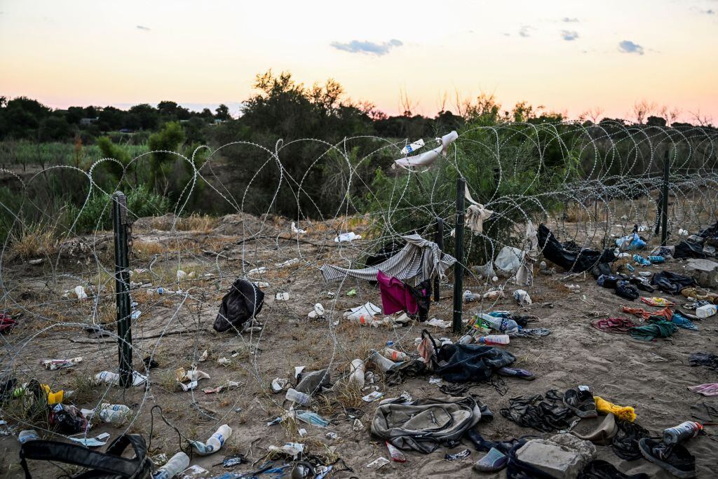 Migrantes dejan pertenencias ante reja divisoria en Estados Unidos