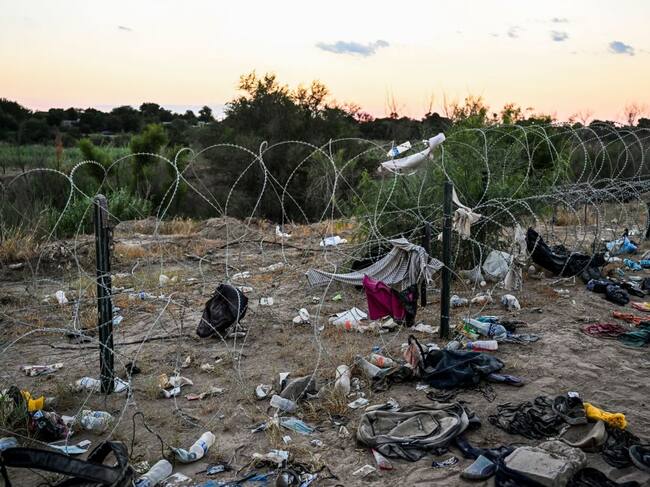 Migrantes dejan pertenencias ante reja divisoria en Estados Unidos