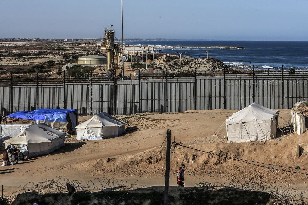 Familias desplazadas sobreviven en Rafah cerca de la reja de separación instalada por Israel en Palestina, desde donde se puede ver el Mar Mediterráneo.