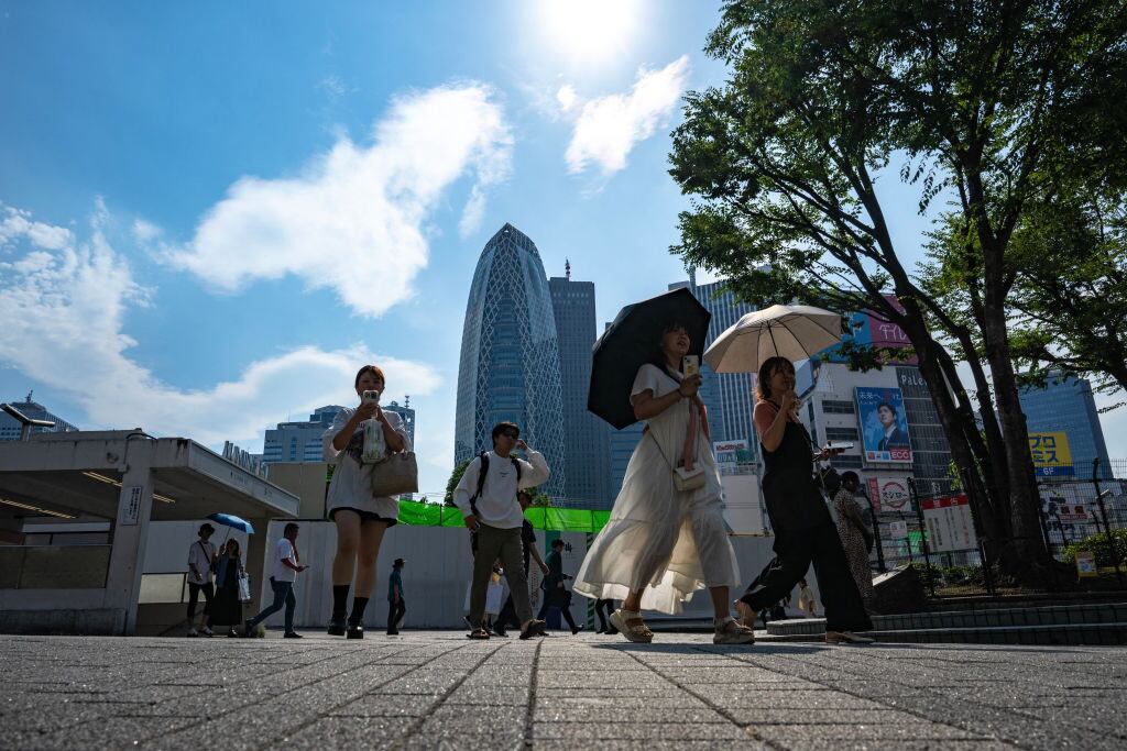 Personas caminan en la ciudad de Tokio con paraguas para enfrentar las altas temperaturas que se detectan en Japón.
