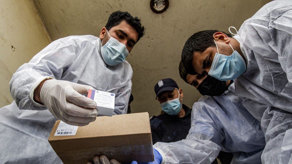 Palestinian health workers unload the first arriving shipment of doses of Russia's Sputnik V vaccine for COVID-19 coronavirus disease, on the Palestinian side of the Kerem Shalom border crossing south of Rafah in the southern Gaza Strip on February 17, 2021. (Photo by SAID KHATIB / AFP) (Photo by SAID KHATIB/AFP via Getty Images)