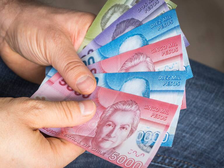 a man holding Chilean money in his hand, Pesos of various values