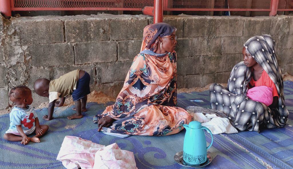 Mujeres y niños en un campo de refugiados en Sudán esperan la entrega de alimentos.