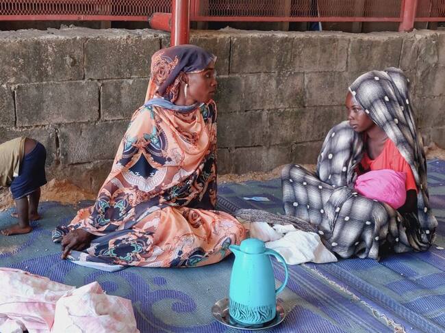 Mujeres y niños en un campo de refugiados en Sudán esperan la entrega de alimentos.