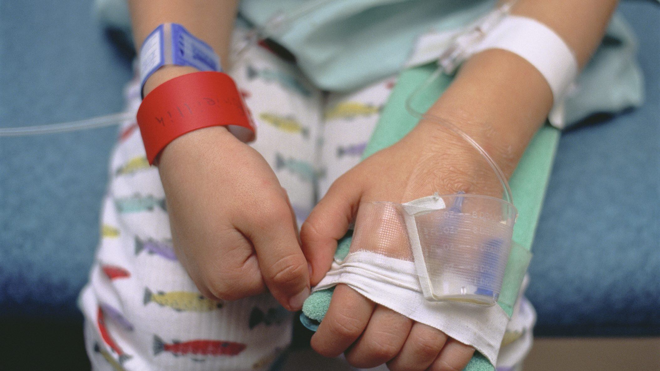 A worried young boy in a hospital bed being treated for croup.The red bracelet is to notify healthcare professionals of an allergy to penicillin.