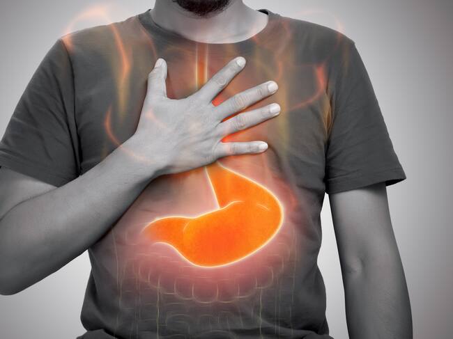 A man burning sensation in chest from acid reflux on gray background.