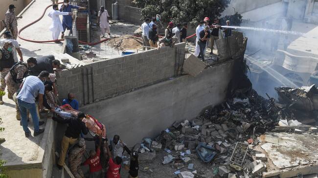 Rescue workers move a body from the site after a Pakistan International Airlines aircraft after crashed at a residential area in Karachi on May 22, 2020. - A Pakistan passenger plane with more than 100 people believed to be on board crashed in the southern city of Karachi on May 22, the country's aviation authority said. (Photo by Asif HASSAN / AFP) (Photo by ASIF HASSAN/AFP via Getty Images)