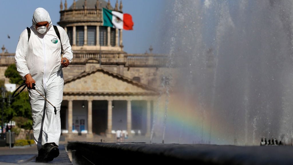 TOPSHOT - A worker wearing a protective suit sprays disinfectant during a campaign to sanitize public spaces as a preventive measure against the spread of the new coronavirus, COVID-19, in Guadalajara, Mexico, on March 20, 2020. (Photo by ULISES RUIZ / AFP) (Photo by ULISES RUIZ/AFP via Getty Images)