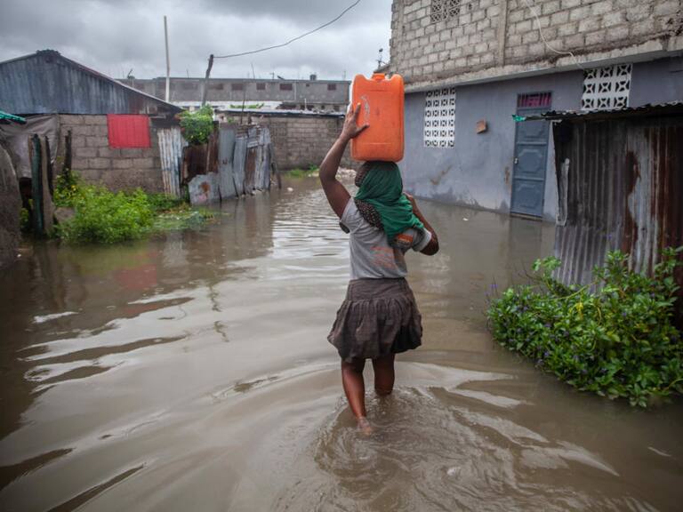 Mujer camina por las calles inundadas tras el paso de una tormenta por Haití