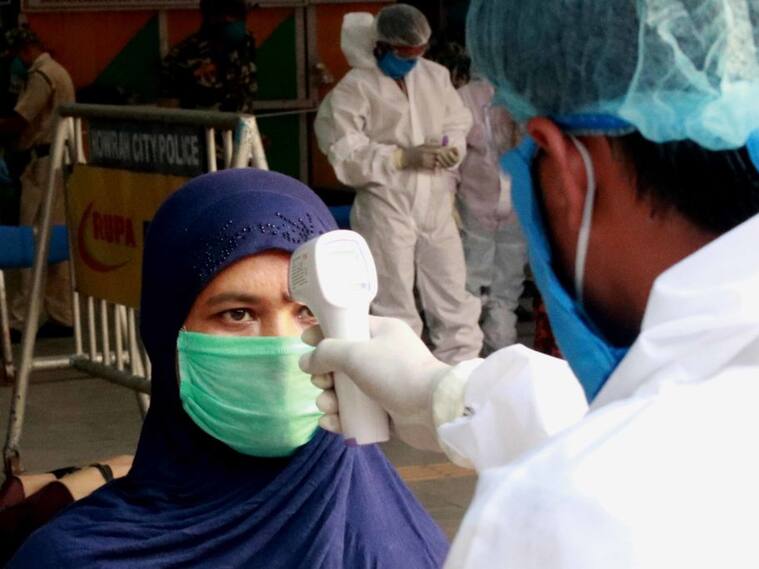 Trabajador mide la temperatura en una estación de trenes en India