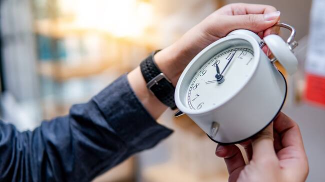 Male hand adjusting or changing the time on white clock. Time management concept.