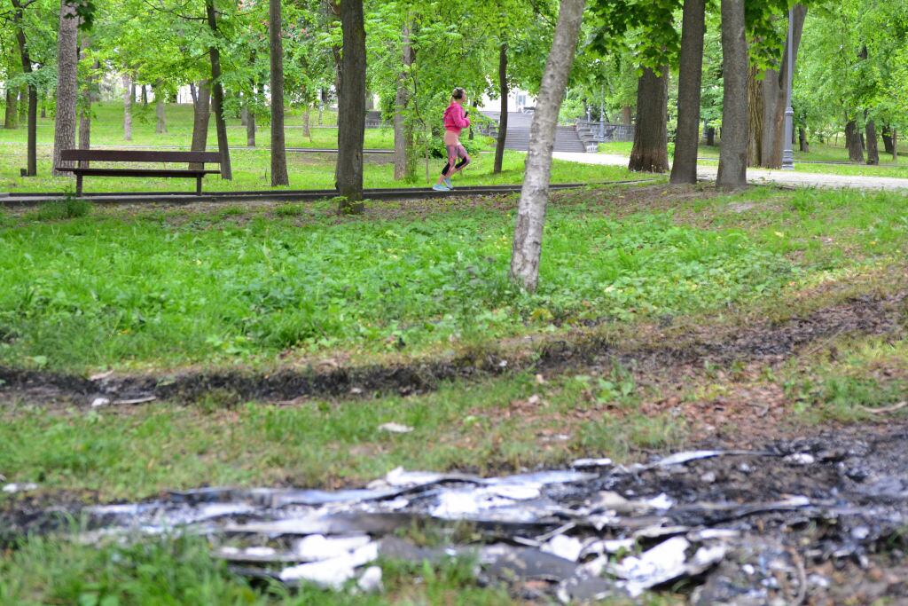 Mujer corre por parque donde se ven los restos de un dron en Ucrania
