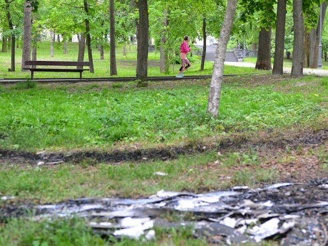 Mujer corre por parque donde se ven los restos de un dron en Ucrania