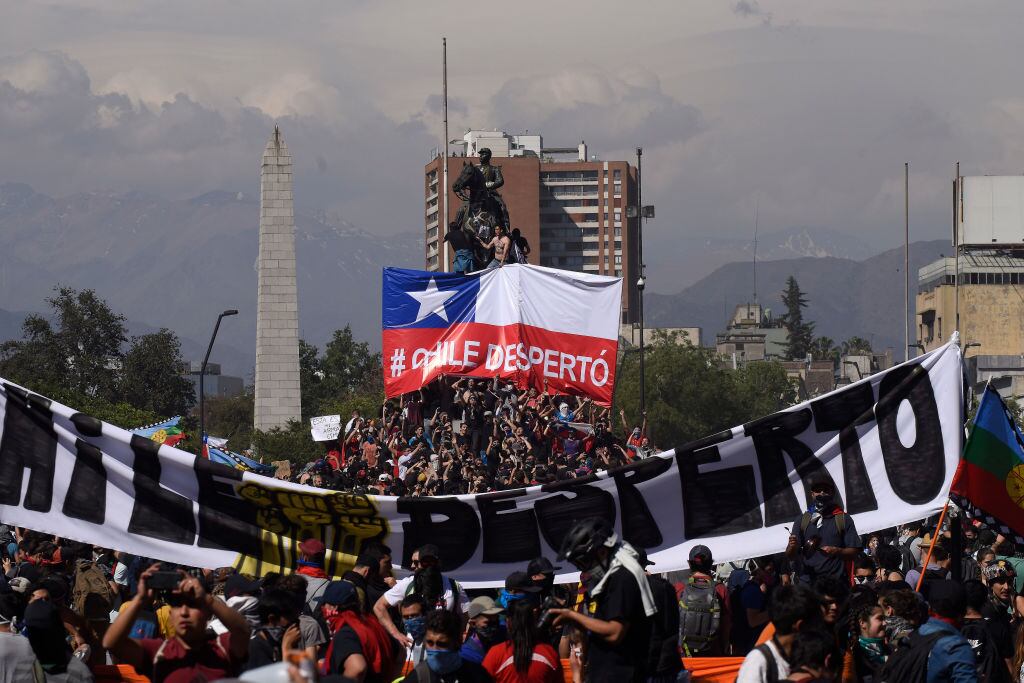 SANTIAGO, CHILE - OCTOBER 22: Demonstrators hold a sign that reads 'Chile is awake' during the fifth day of protests against President Sebastian Piñera on October 22, 2019 in Santiago, Chile. After President Sebastian Piñera suspended the 3.5% subway fare hike and declared the state of emergency protest developed into looting and arson, generating chaos in Santiago, Valparaiso and a dozen other cities resulting in at least 13 dead and over 2000 arrested. Demands behind the protest include issues like health care, pension system, privatization of water, public transport, education, social mobility and corruption. (Photo by Claudio Santana/Getty Images)