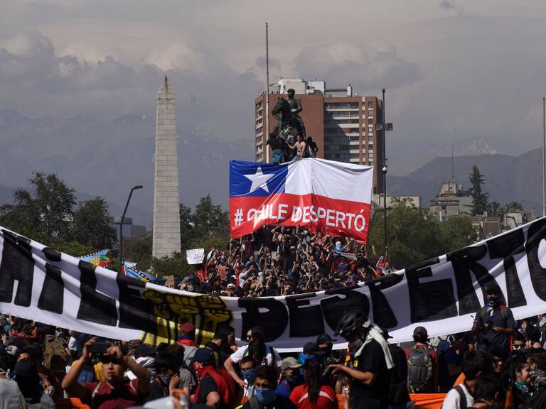SANTIAGO, CHILE - OCTOBER 22: Demonstrators hold a sign that reads 'Chile is awake' during the fifth day of protests against President Sebastian Piñera on October 22, 2019 in Santiago, Chile. After President Sebastian Piñera suspended the 3.5% subway fare hike and declared the state of emergency protest developed into looting and arson, generating chaos in Santiago, Valparaiso and a dozen other cities resulting in at least 13 dead and over 2000 arrested. Demands behind the protest include issues like health care, pension system, privatization of water, public transport, education, social mobility and corruption. (Photo by Claudio Santana/Getty Images)