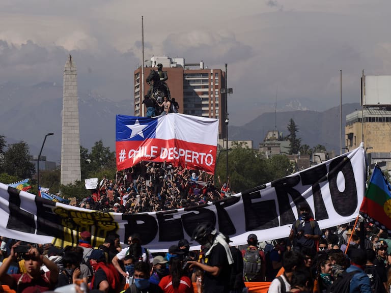 SANTIAGO, CHILE - OCTOBER 22: Demonstrators hold a sign that reads &#039;Chile is awake&#039; during the fifth day of protests against President Sebastian Piñera on October 22, 2019 in Santiago, Chile. After President Sebastian Piñera suspended the 3.5% subway fare hike and declared the state of emergency protest developed into looting and arson, generating chaos in Santiago, Valparaiso and a dozen other cities resulting in at least 13 dead and over 2000 arrested. Demands behind the protest include issues like health care, pension system, privatization of water, public transport, education, social mobility and corruption. (Photo by Claudio Santana/Getty Images)
