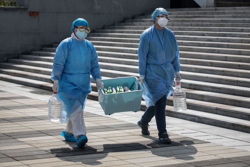 Funcionarios médicos transportan muestras del Covid-19 en Wuhan